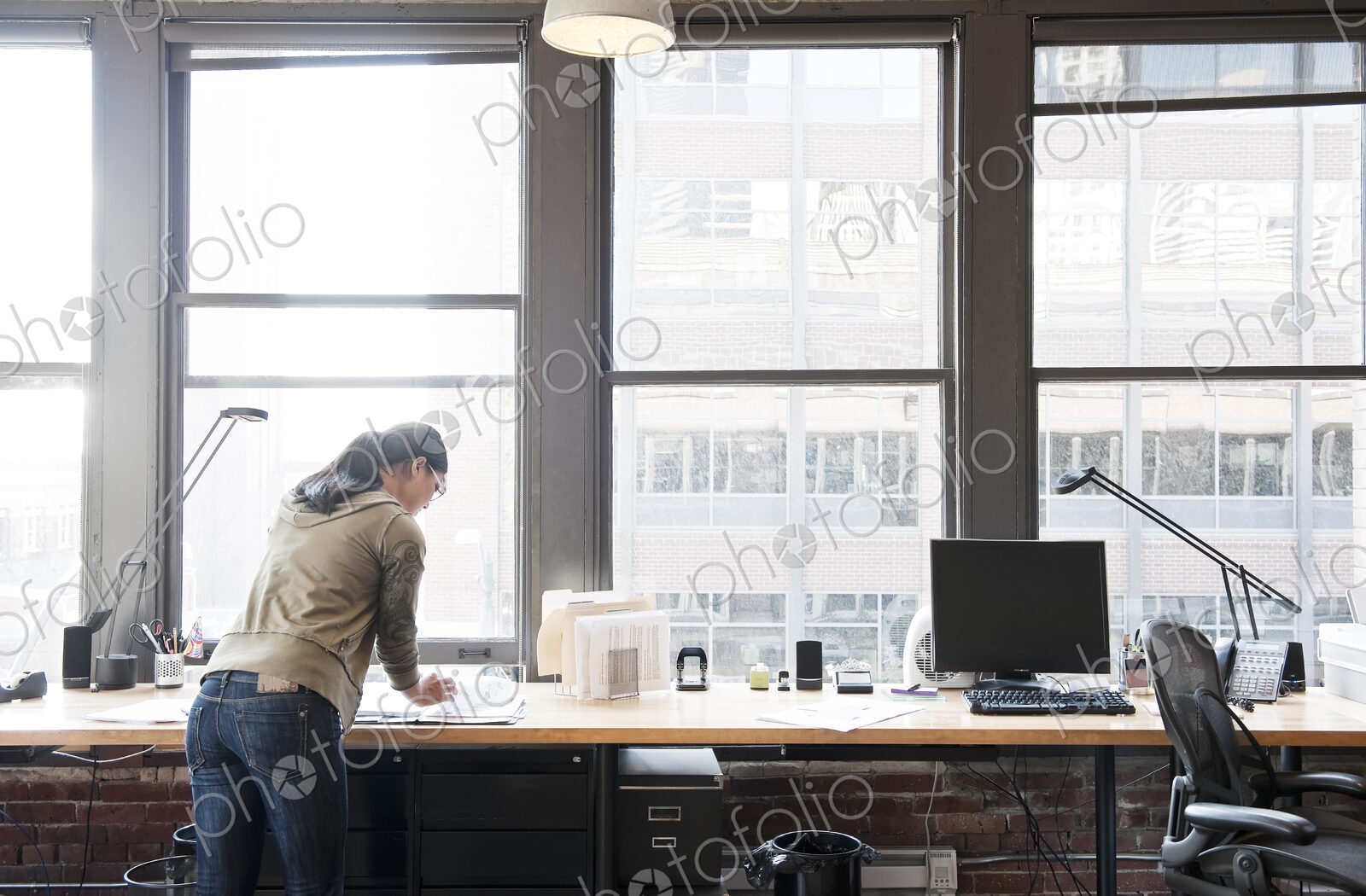 Asian woman working at her office workstation in a creative office.