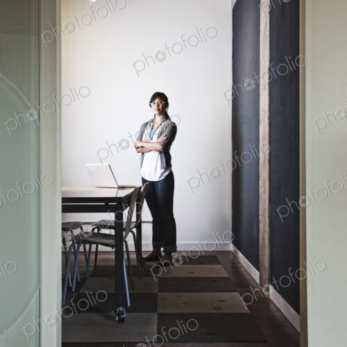 Asian woman working on a laptop computer in a small conference room. Asian woman working on a laptop computer in a small conference room.