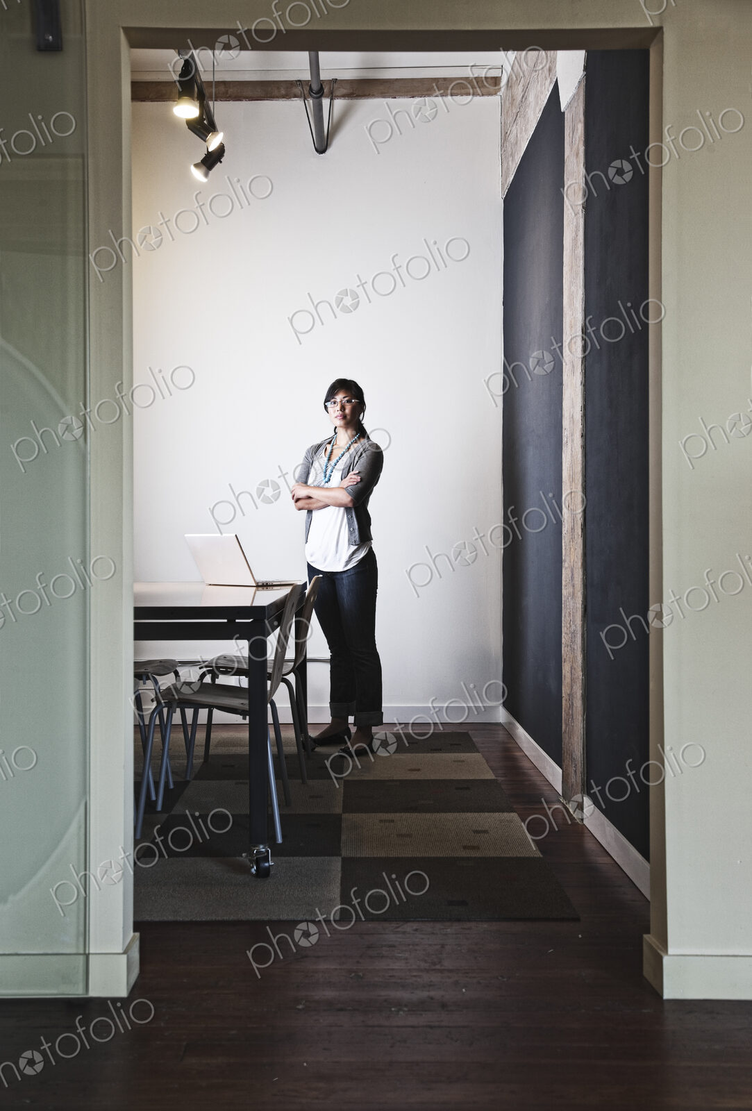 Asian woman working on a laptop computer in a small conference room.