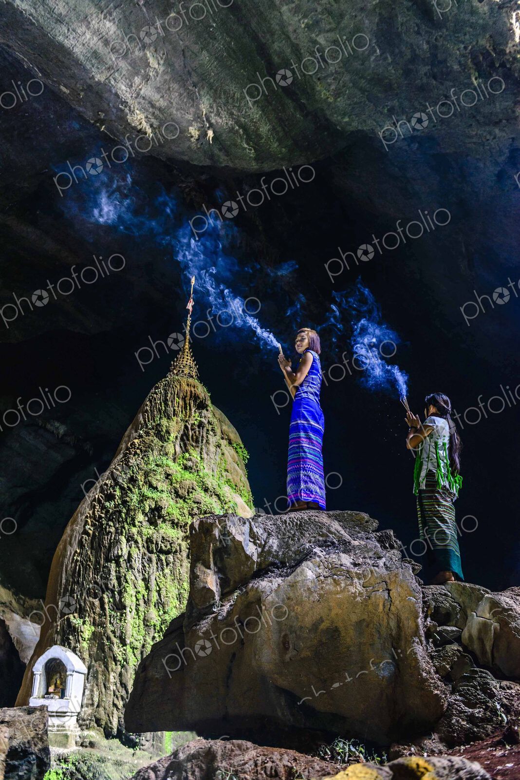 Asian women burning incense on rock formation in cave temple