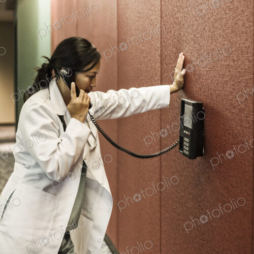 Asiasn woman doctor on a phone in a hospital lobby. Asiasn woman doctor on a phone in a hospital lobby.