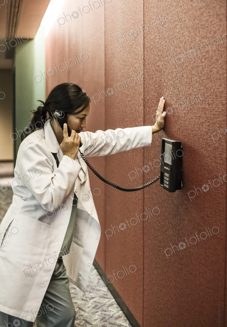 Asiasn woman doctor on a phone in a hospital lobby.