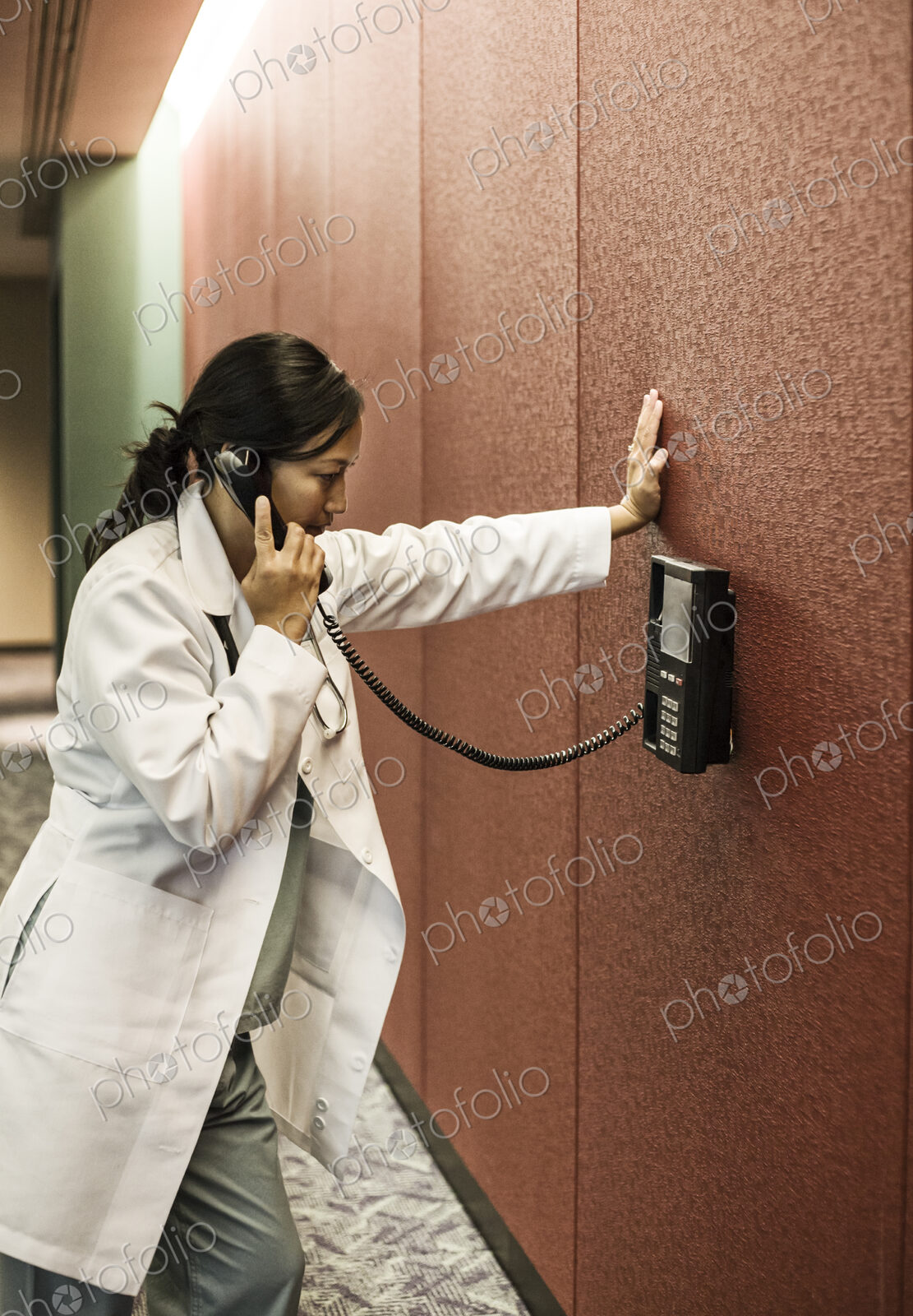 Asian woman doctor on a phone in a hospital lobby.