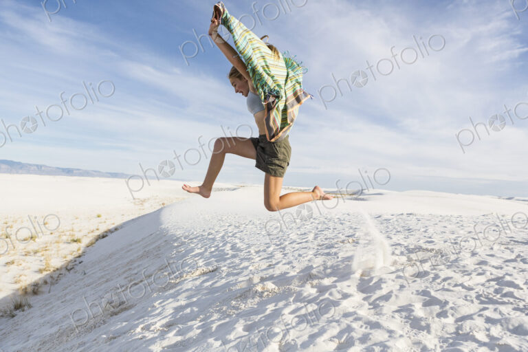 Athletic 13 year old girl leaping in the sand, White Sands Nat'l Monument, NM