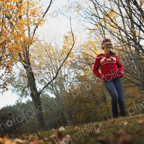 Autumn foliage on the trees on a farm. A young girl in a red knitted jumper with a… Autumn foliage on the trees on a farm. A young girl in a red knitted jumper with a…