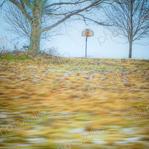 Autumn leaves blowing across a sports field.