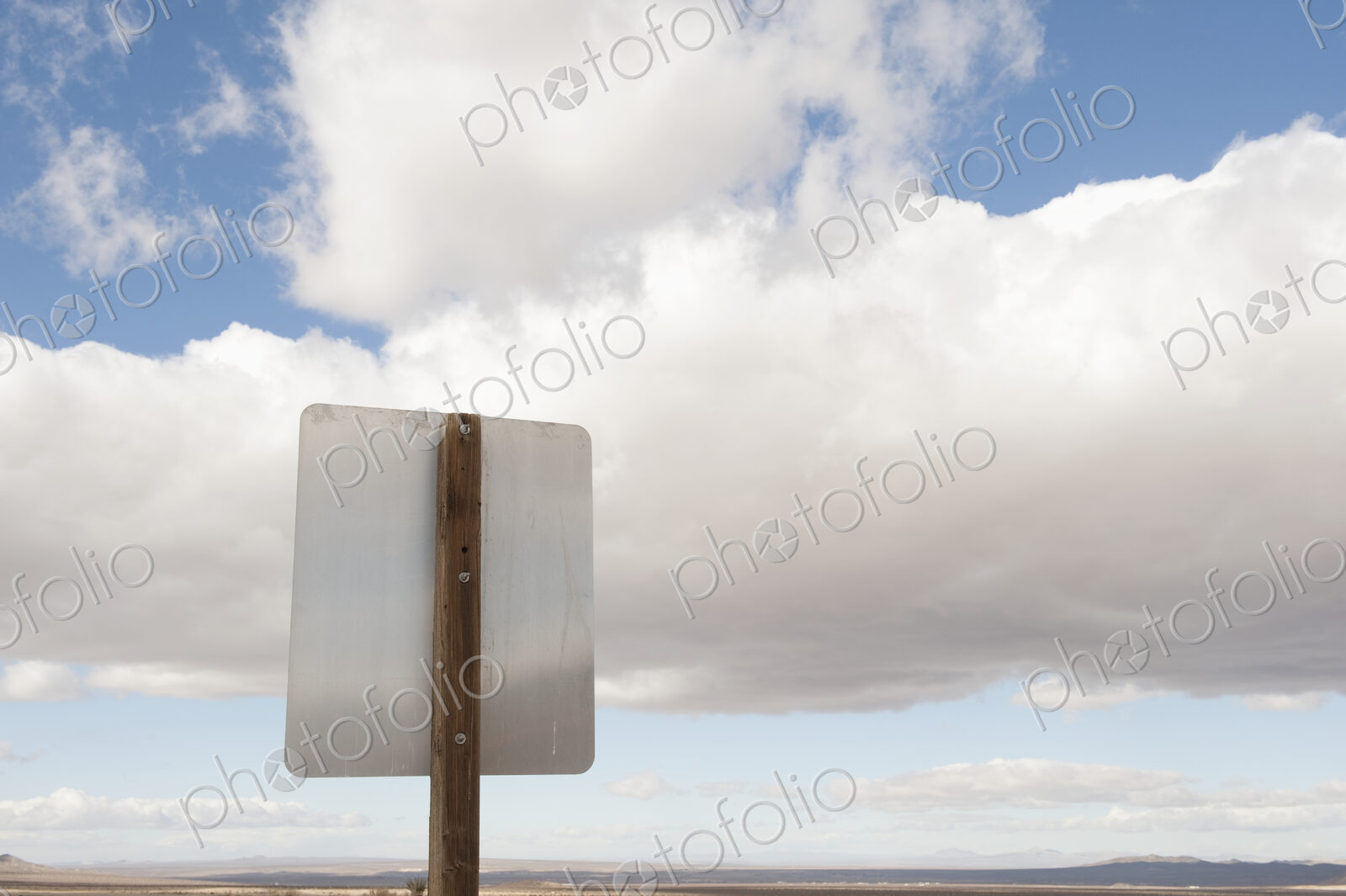 Back of road sign against blue sky and clouds