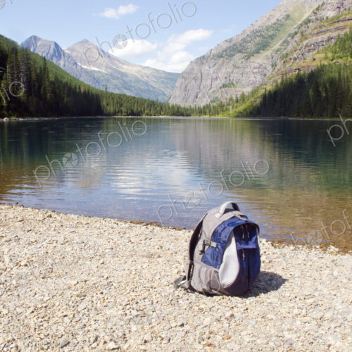 Backpack at mountain lake, Glacier National Park, Montana, United States Backpack at mountain lake, Glacier National Park, Montana, United States