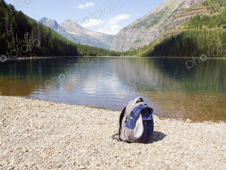 Backpack at mountain lake, Glacier National Park, Montana, United States