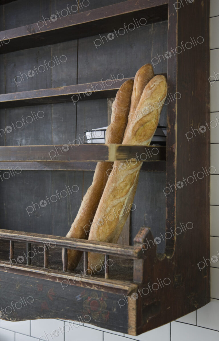 Baguettes in wooden wall rack at a restaurant.