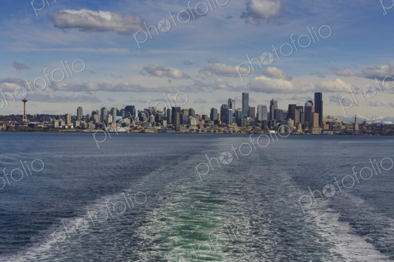 Baingbridge Ferry wake and skyline view of Seattle and the Cascade mountains in the…