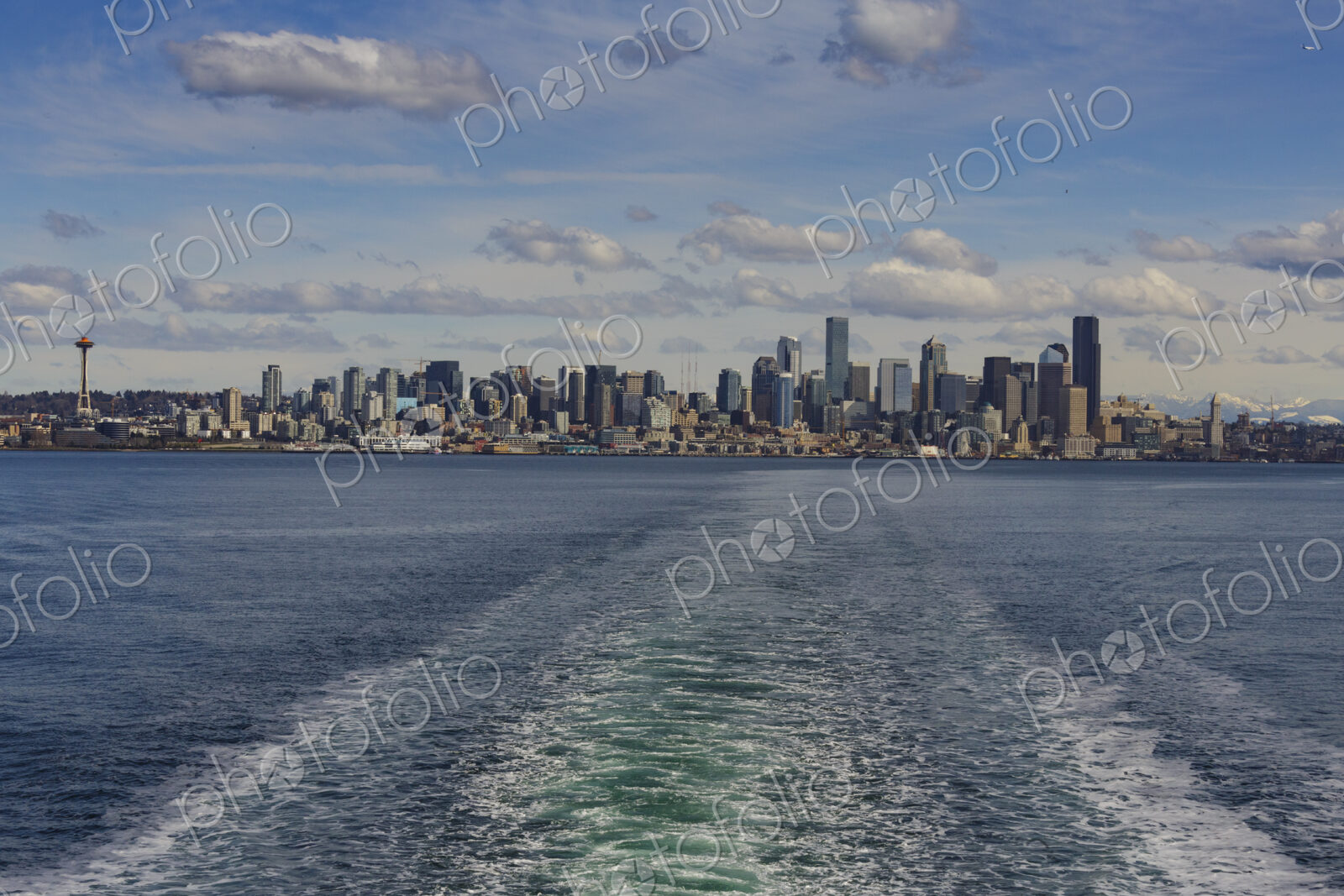 Baingbridge Ferry wake and skyline view of Seattle and the Cascade mountains in the…
