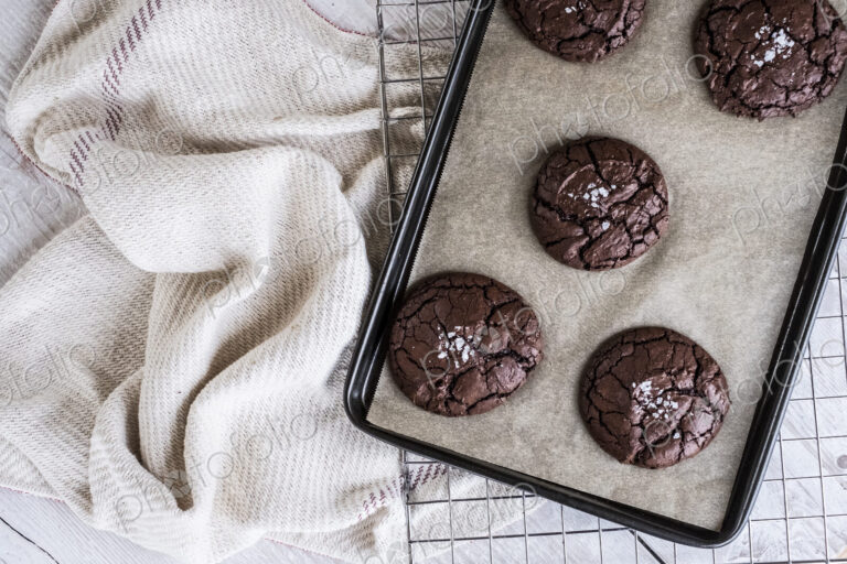 Baked chocolate brownies on a baking tray placed on a wire cooling rack.