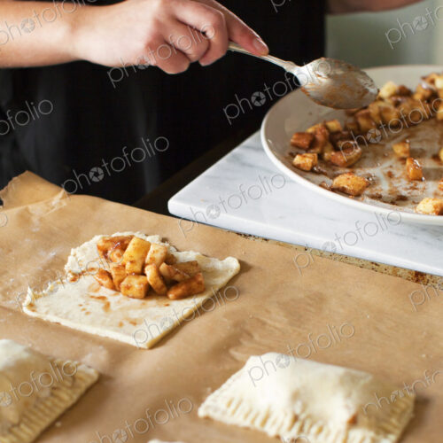 Baker filling miniature apple pies