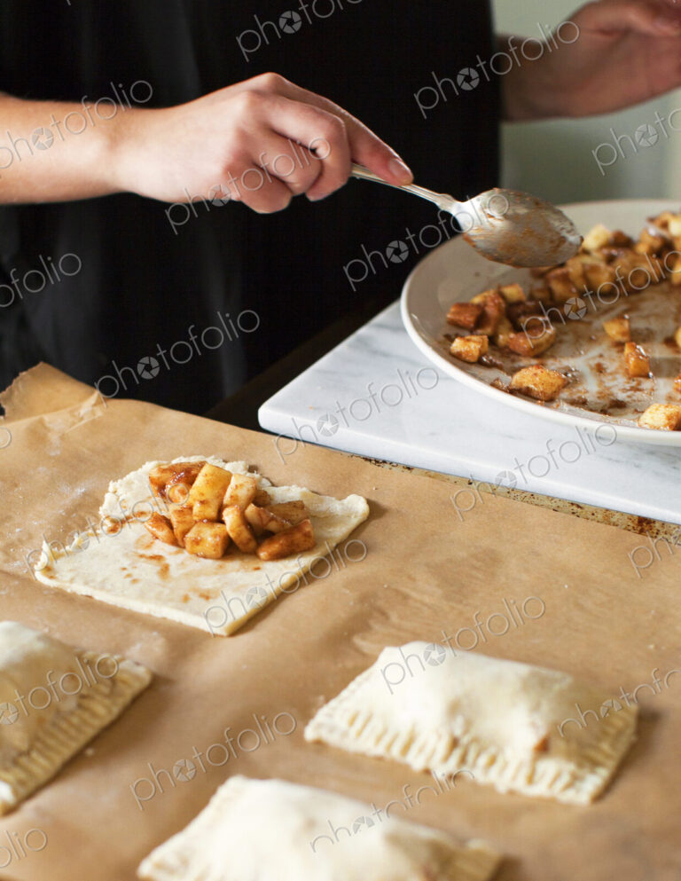Baker filling miniature apple pies