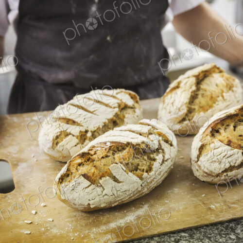 Baker holding tray with freshly baked loaves of bread. Baker holding tray with freshly baked loaves of bread.