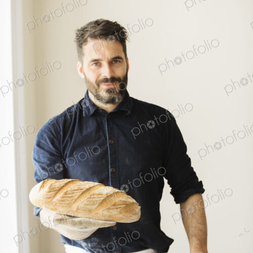 Baker holding two freshly baked loaves of bread. Baker holding two freshly baked loaves of bread.
