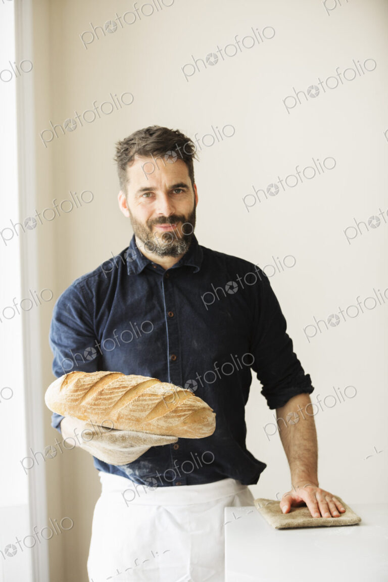 Baker holding two freshly baked loaves of bread.