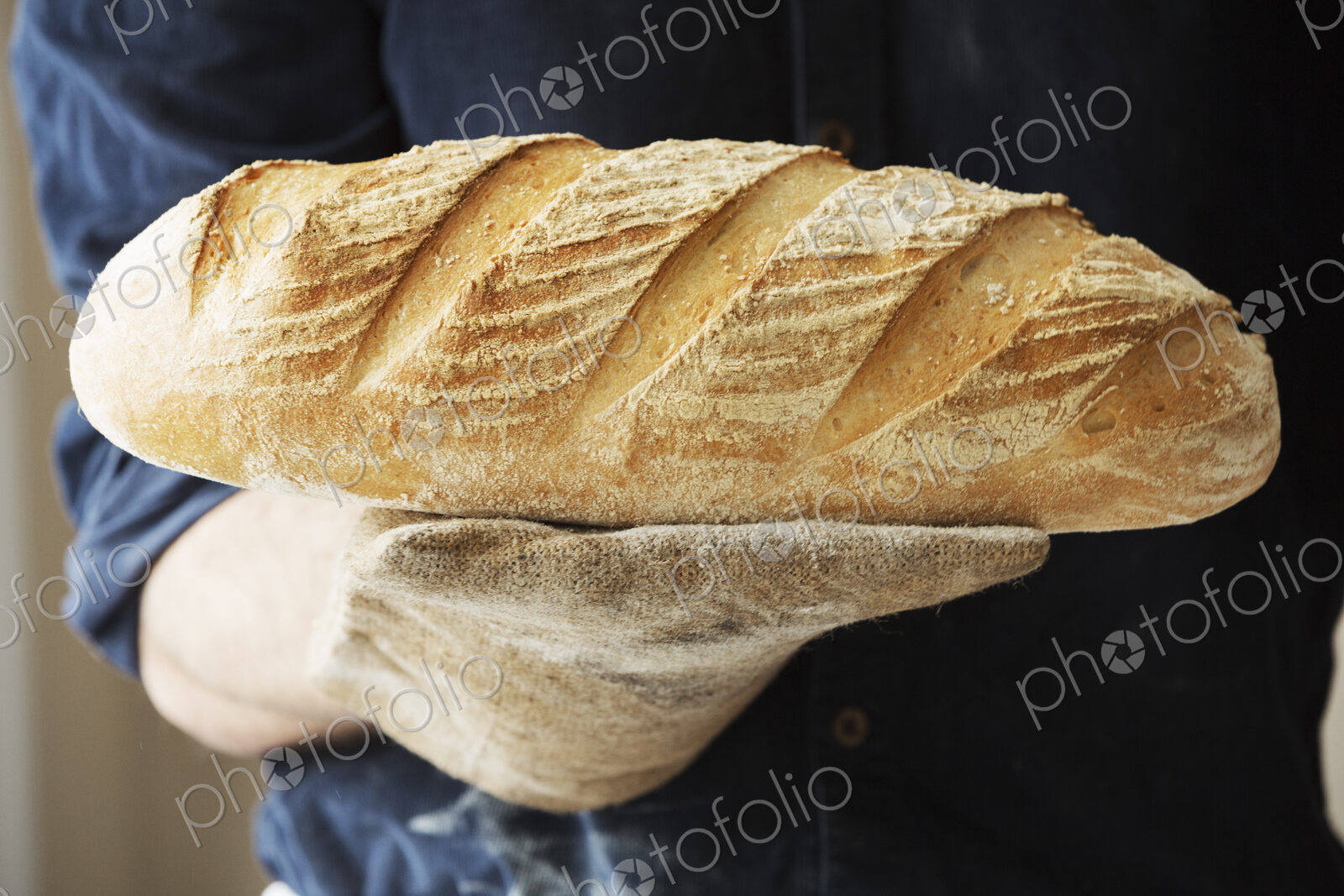 Baker holding two freshly baked loaves of bread.