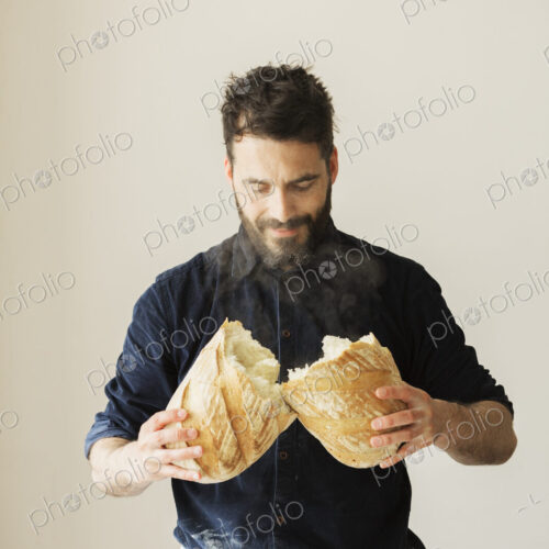 Baker holding two freshly baked loaves of bread.
