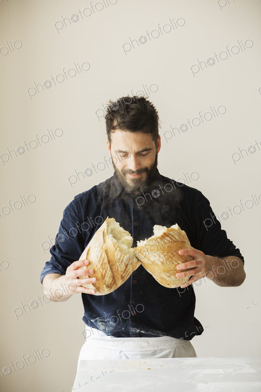 Baker holding two freshly baked loaves of bread.