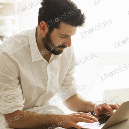 Baker wearing an apron sitting at a laptop computer, typing. Baker wearing an apron sitting at a laptop computer, typing.