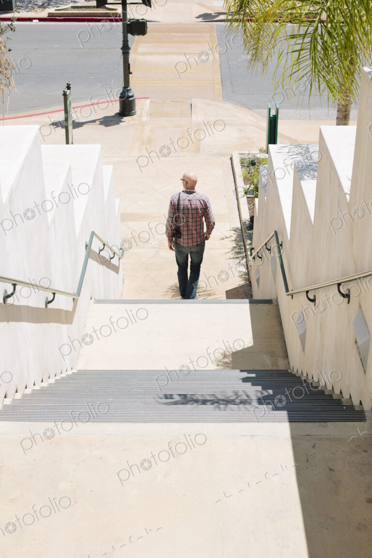 Bald man walking down a staircase.