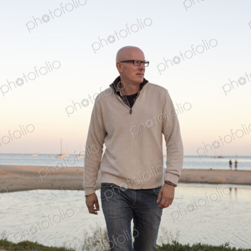 Bald man walking on a sandy beach by the ocean. Bald man walking on a sandy beach by the ocean.