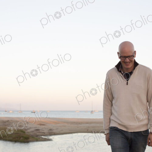 Bald man walking on a sandy beach by the ocean. Bald man walking on a sandy beach by the ocean.