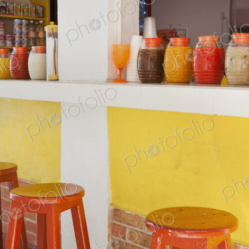 Bar stools,and rows of juice bottles, market stall and drinks stand Bar stools,and rows of juice bottles, market stall and drinks stand