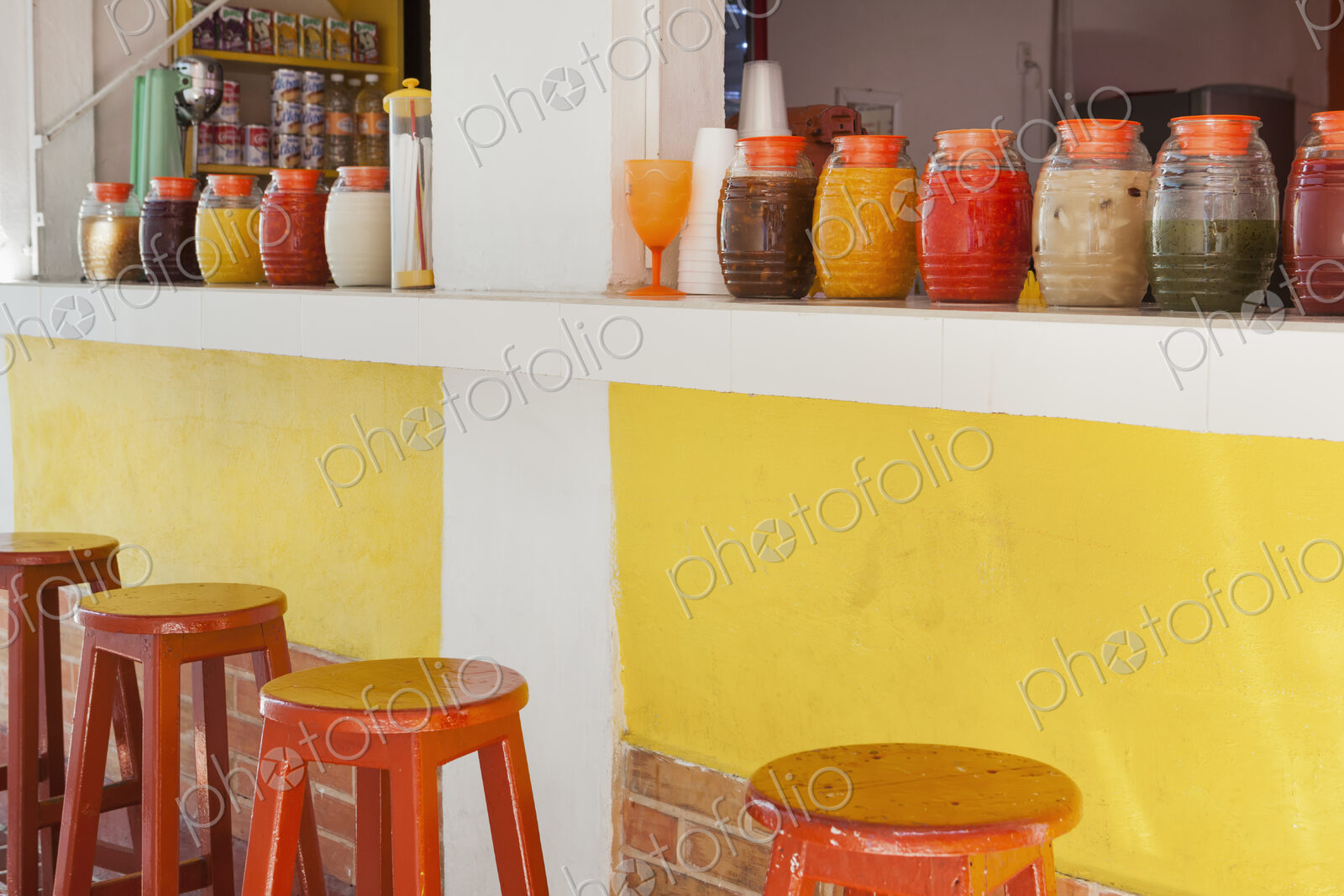 Bar stools,and rows of juice bottles, market stall and drinks stand