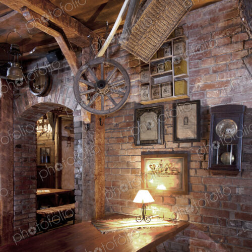 Bar with exposed brickwork and cart wheel, basket and old photographs at night Bar with exposed brickwork and cart wheel, basket and old photographs at night