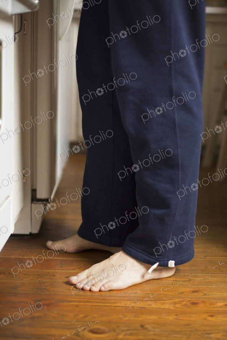 Barefoot man standing in a kitchen.