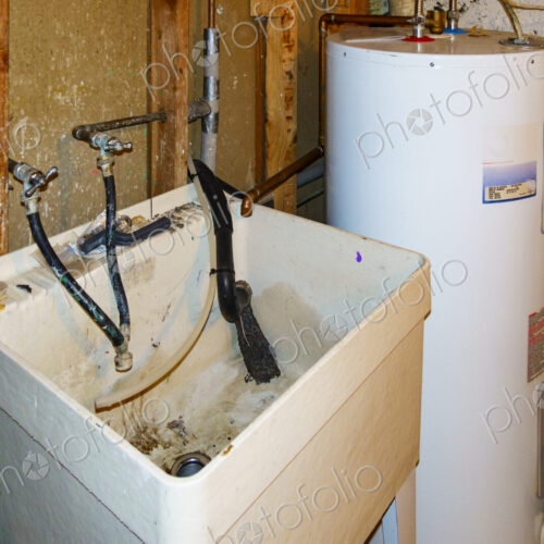 Basement corner with a hot water heater and muddy sink. Basement corner with a hot water heater and muddy sink.