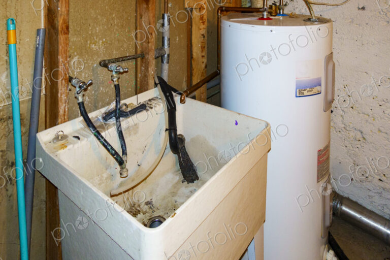 Basement corner with a hot water heater and muddy sink.