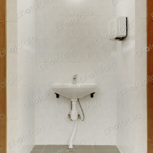 Basin and hot air hand dryer in the changing rooms of a sporting venue.