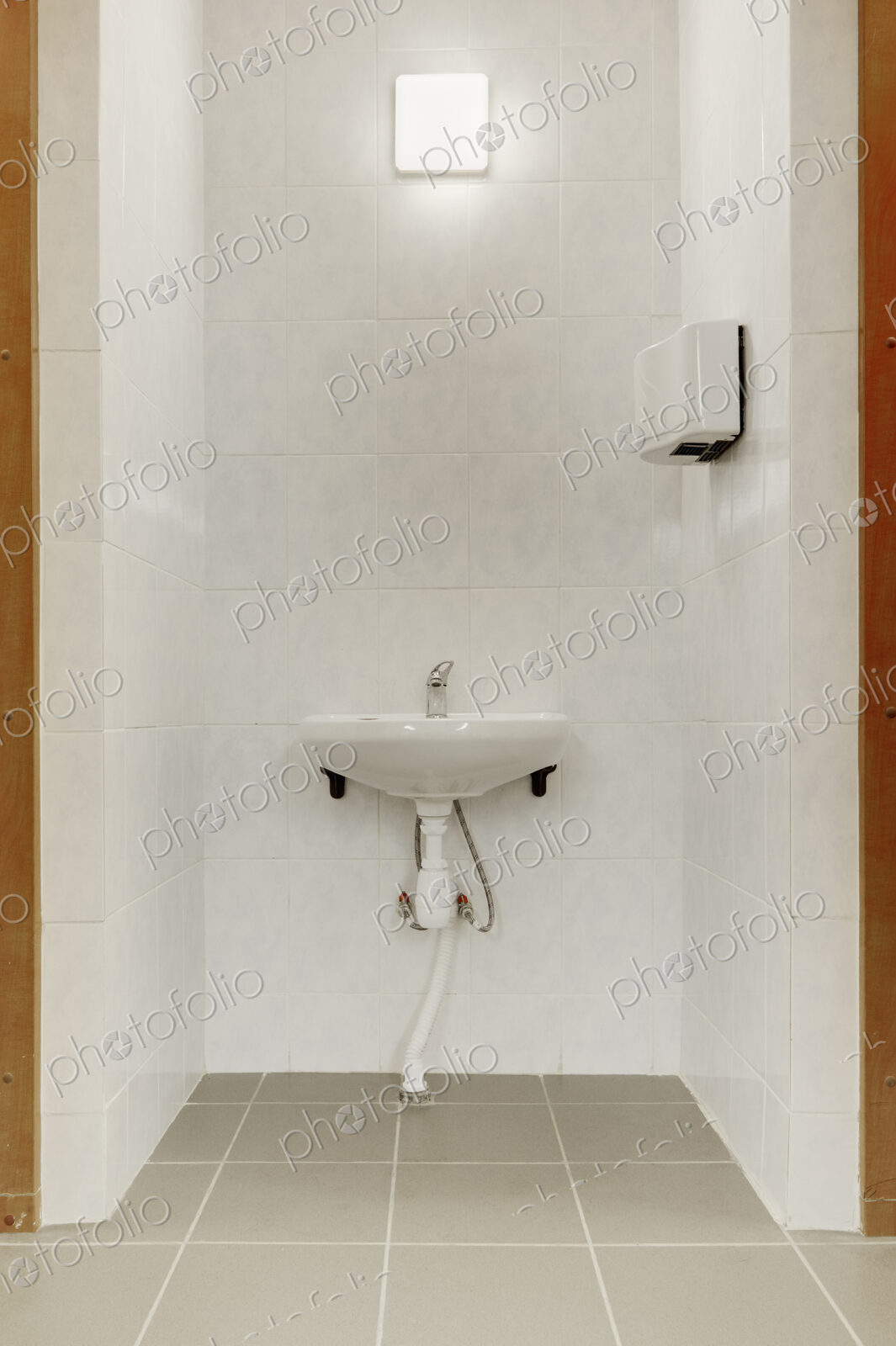 Basin and hot air hand dryer in the changing rooms of a sporting venue.