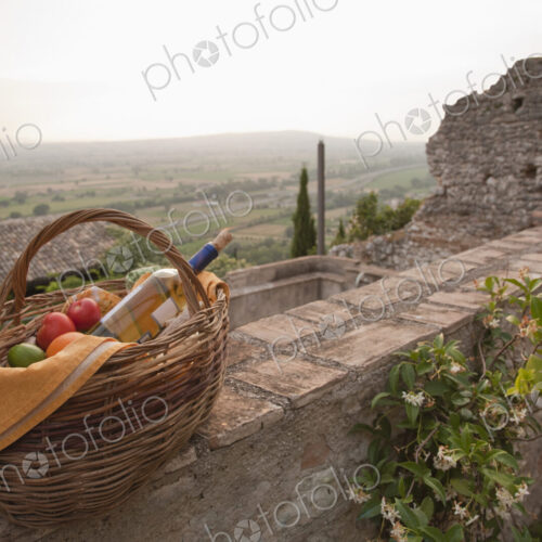 Basket of fresh fruit and wine on stone wall
