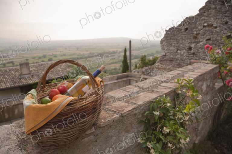 Basket of fresh fruit and wine on stone wall
