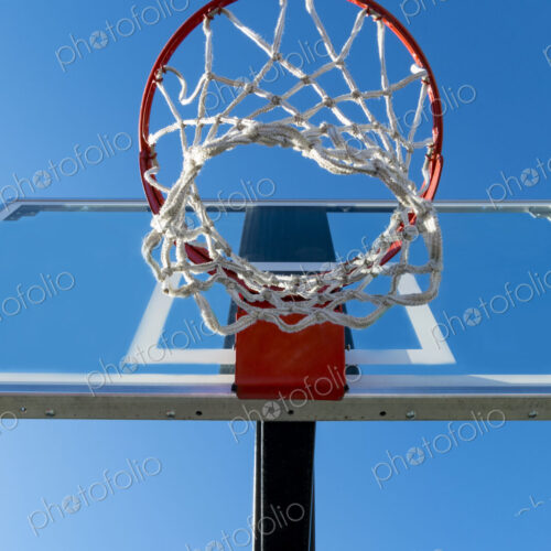 Basketball hoop and backboard, low angle view, against a blue sky.