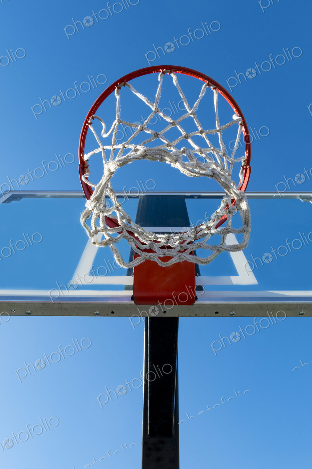 Basketball hoop and backboard, low angle view, against a blue sky.