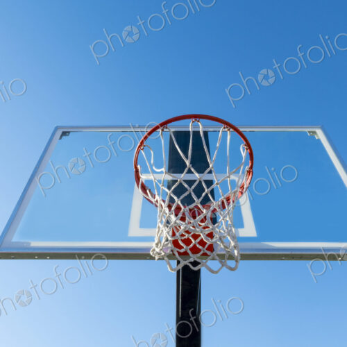 Basketball hoop and backboard, low angle view, against a blue sky.