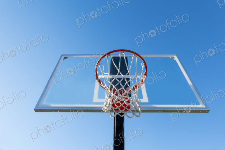 Basketball hoop and backboard, low angle view, against a blue sky.