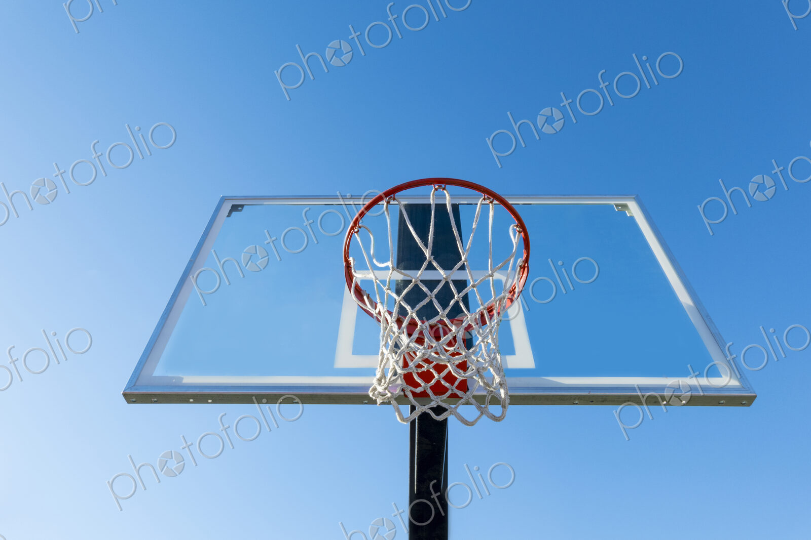 Basketball hoop and backboard, low angle view, against a blue sky.