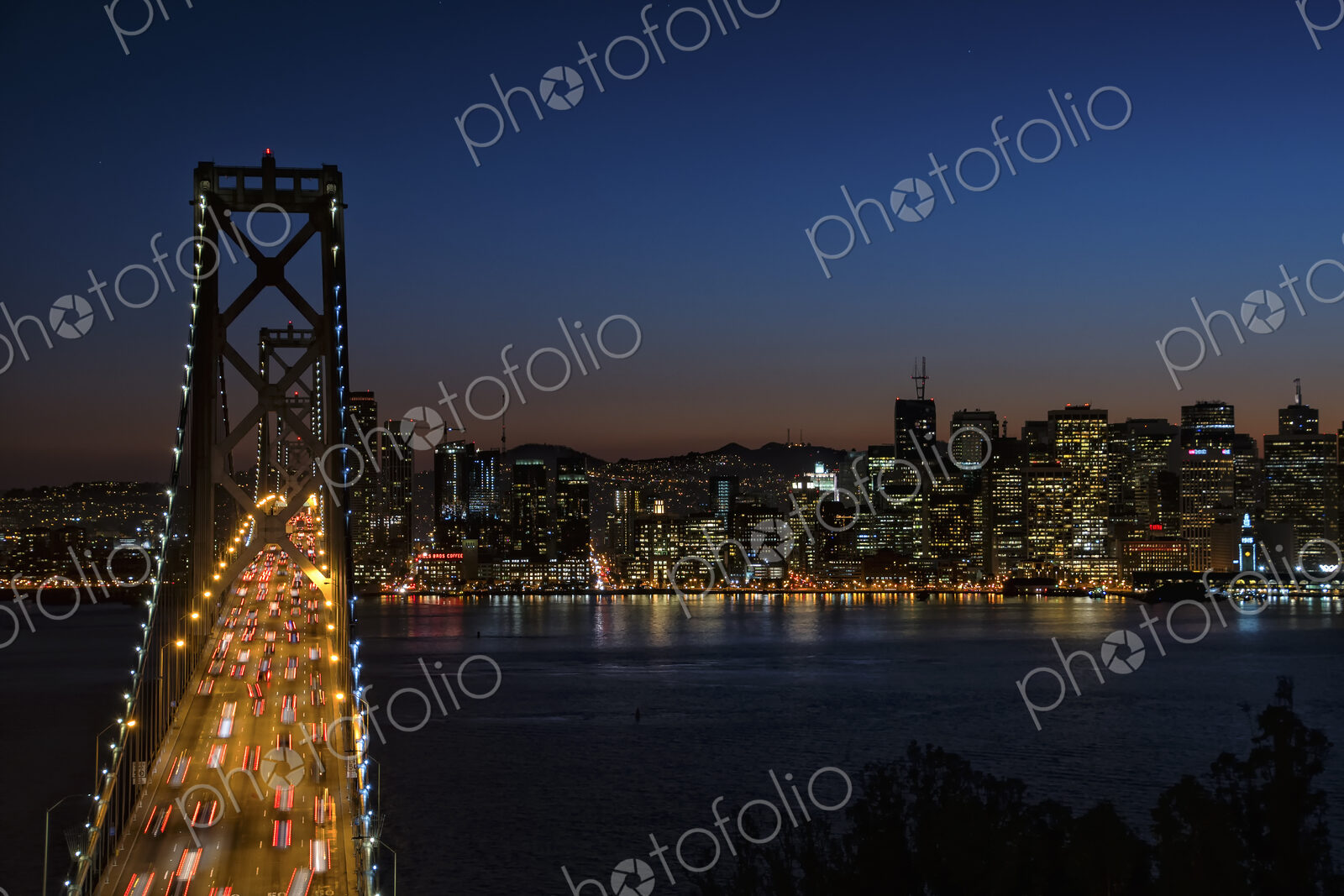 Bay Bridge at night, seen from above, traffic lit up, and the lights of the…