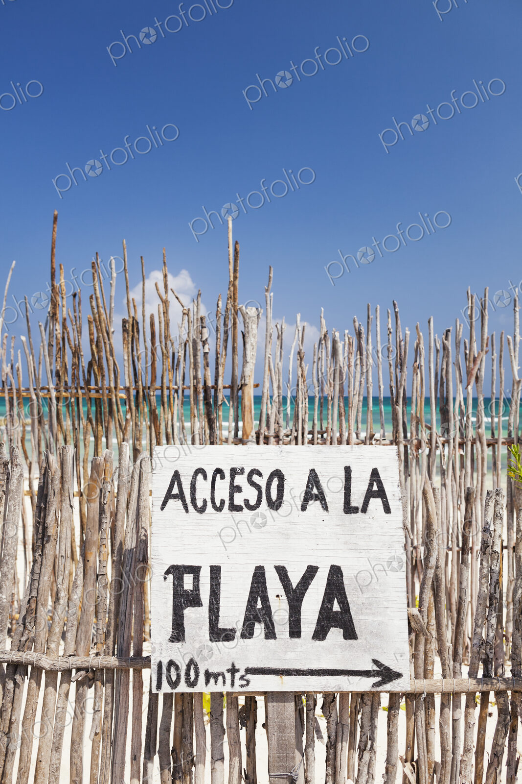 Beach access sign in Spanish,on a fence by the beach