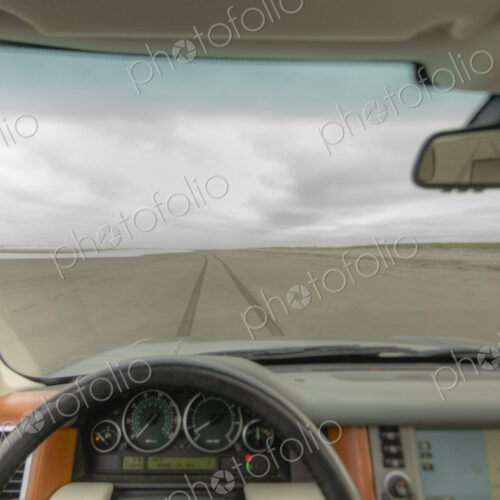 Beach and cliffs seen from driver's seat of a car, with steering wheel in foreground. Beach and cliffs seen from driver's seat of a car, with steering wheel in foreground.