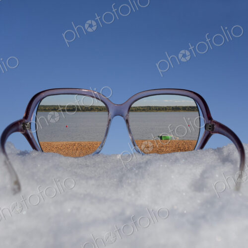 Beach and lakeside seen in reflection in sunglasses on thick snow.