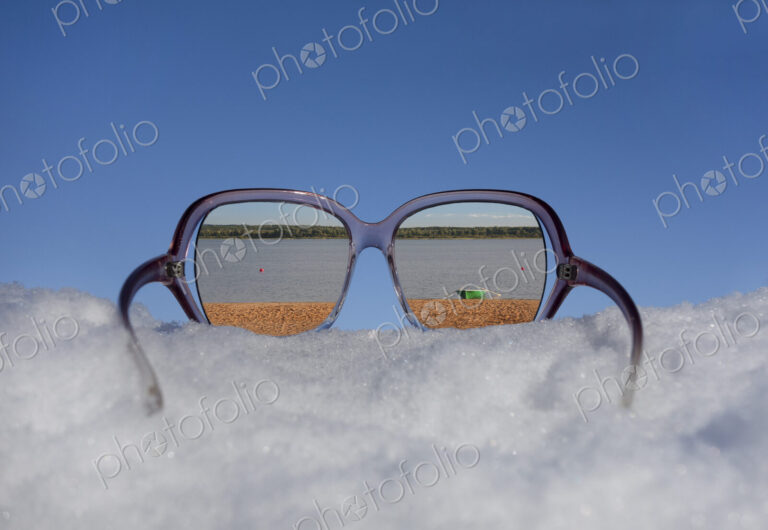Beach and lakeside seen in reflection in sunglasses on thick snow.
