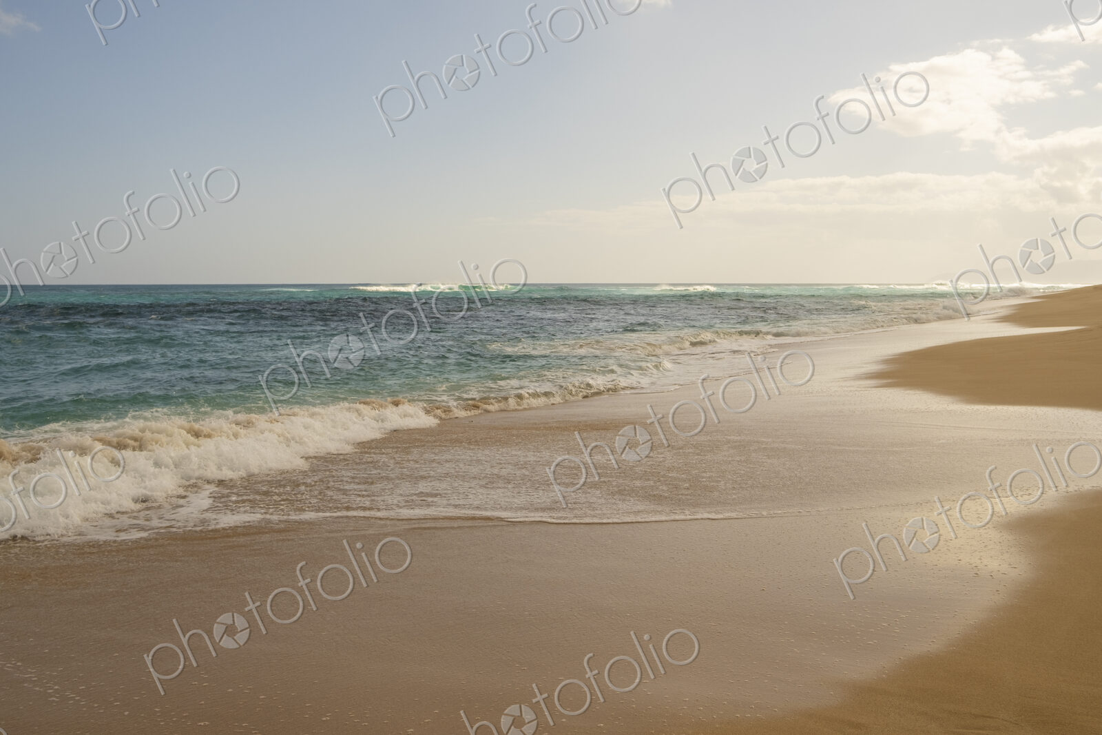 Beach and surf along Oahu’s wild North Shore with waves breaking far from the shore.